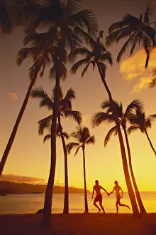 Images Dated 21st January 1999: Couple Runs Together Holding Hands, Golden Sunset, Palm Trees, Ocean In Background