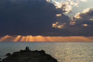 Dramatic Sky With Orange Sun Rays Reaching Down To The Water On The Horizon Out Of Dramatic Sky With Orange Sun Rays Reaching Down To The Water On The Horizon Out Of