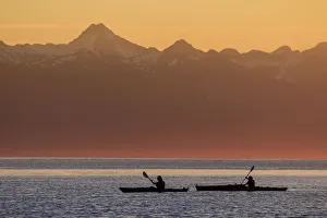 Two Female Sea Kayakers Enjoy A Warm Summer Evening While Paddling In Favorite Passage, Alaska Two Female Sea Kayakers Enjoy A Warm Summer Evening While Paddling In Favorite Passage, Alaska