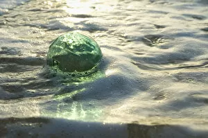 Images Dated 24th December 2005: A Glass Fishing Ball Floats In Shallow Water, Bright Reflections