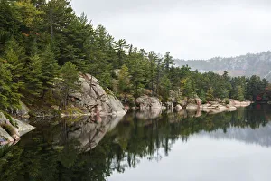 Green Coniferous Forest On A Tranquil Lake Shore With Red Rock Geological Formations; Killarney, Ontario, Canada Green Coniferous Forest On A Tranquil Lake Shore With Red Rock Geological Formations; Killarney, Ontario, Canada