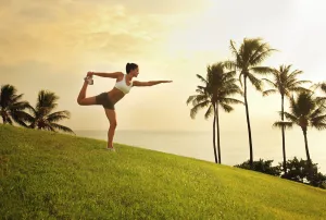Hawaii, Oahu, Female Doing A Yoga Pose, Stretching On A Hill Overlooking Ocean, Palm Trees And Sunset Hawaii, Oahu, Female Doing A Yoga Pose, Stretching On A Hill Overlooking Ocean, Palm Trees And Sunset