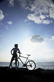 Hawaii, Oahu, Silhouette Of A Woman With A Bike On A Rocky Coastline Hawaii, Oahu, Silhouette Of A Woman With A Bike On A Rocky Coastline
