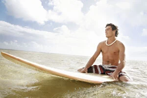 Images Dated 29th November 2009: Hawaii, Oahu, Young Man Sitting On His Surfboard At The Shoreline