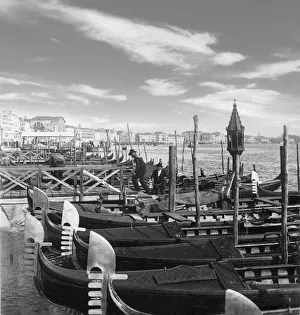 Historic image in black and white of gondolas and gondoliers working at a pier circa 1902 in Venice; Venice, Italy Historic image in black and white of gondolas and gondoliers working at a pier circa 1902 in Venice; Venice, Italy