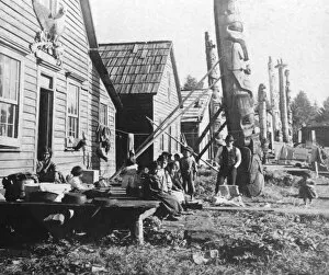 Historic image in black and white of native indian children with houses and totem poles; Alaska