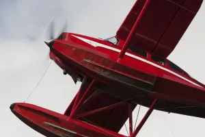 Low Angle View Of A Red Float Plane Against A Cloudy Sky; Alaska, United States Of America Low Angle View Of A Red Float Plane Against A Cloudy Sky; Alaska, United States Of America