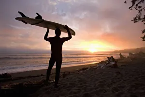 A Man Carrying His Surfboard; Sombrio Beach, Vancouver Island, British Columbia, Canada A Man Carrying His Surfboard; Sombrio Beach, Vancouver Island, British Columbia, Canada