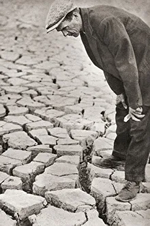A man standing in the reservoir at Kettering, Northamptonshire, surveying its sun-baked bottom following the summer' A man standing in the reservoir at Kettering, Northamptonshire, surveying its sun-baked bottom following the summer'