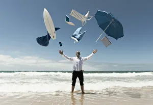 A Man Stands In The Ocean With Items From Work And Vacation Flying Over His Head; Tarifa, Cadiz, Andalusia, Spain A Man Stands In The Ocean With Items From Work And Vacation Flying Over His Head; Tarifa, Cadiz, Andalusia, Spain