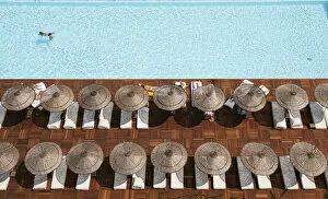 Man Swimming In Pool By Sunloungers, Aerial View