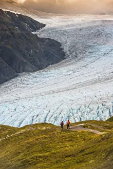 A Man And Woman Hiking Down The Harding Icefield Trail With Exit Glacier In The Background, Kenai Fjords National Park A Man And Woman Hiking Down The Harding Icefield Trail With Exit Glacier In The Background, Kenai Fjords National Park