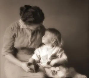 Mother sits with her toddler daughter and a holds a toy as they look at each other Mother sits with her toddler daughter and a holds a toy as they look at each other