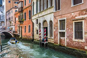 Motorboat travelling along a canal lined with historical buildings in Venice, Italy Motorboat travelling along a canal lined with historical buildings in Venice, Italy