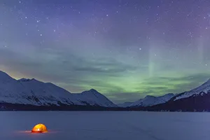 Nighttime View Of A Lit Tent On A Snow Covered Trail Lake With The Moon, Stars, And Northern Lights Overhead Nighttime View Of A Lit Tent On A Snow Covered Trail Lake With The Moon, Stars, And Northern Lights Overhead