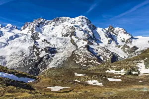 People hiking along the moorlands next to the snow covered mountains of the of the Swiss Alps at Zermatt, Switzerland People hiking along the moorlands next to the snow covered mountains of the of the Swiss Alps at Zermatt, Switzerland
