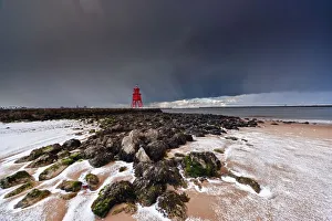 A Red Lighthouse Along The Coast Under A Stormy Sky; South Shields, Tyne And Wear, England A Red Lighthouse Along The Coast Under A Stormy Sky; South Shields, Tyne And Wear, England