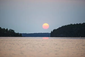 Images Dated 15th August 2013: A Red Sun Setting Over The Forest With A Lake Reflecting The Pink Glow; Manitoba, Canada