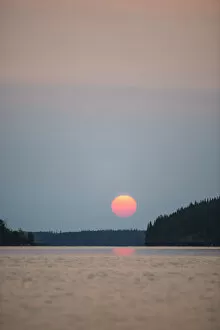 Images Dated 15th August 2013: A Red Sun Setting Over The Forest With A Lake Reflecting The Pink Glow; Manitoba, Canada