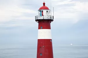 Images Dated 1st August 2012: Red and white lighthouse along the coast with a sailboat in the distance near westkapelle;