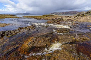Rocky shoreline of a river flowing into the sea bay on the Isle of Skye in Scotland, United Kingdom Rocky shoreline of a river flowing into the sea bay on the Isle of Skye in Scotland, United Kingdom