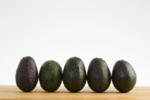 A Row Of Avocados Standing Upright On A Wooden Board; Calgary, Alberta, Canada A Row Of Avocados Standing Upright On A Wooden Board; Calgary, Alberta, Canada