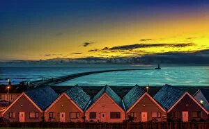 Rooftops Gallery: Row of Houses illuminated at sunset with Roker Pier Lighthouse in the distance, Sunderland, England
