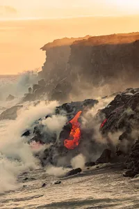 Sea Water And Molten Rock Splatter Together As A Wave Crashes Onto The Pahoehoe Lava Flowing From Kilauea Into The Sea Water And Molten Rock Splatter Together As A Wave Crashes Onto The Pahoehoe Lava Flowing From Kilauea Into The