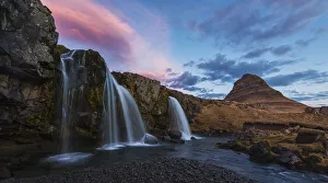Small Waterfall With Kirkjufell In The Distance And Clouds Lit By The Rising Sun; Snaefellsnes Peninsula, Iceland Small Waterfall With Kirkjufell In The Distance And Clouds Lit By The Rising Sun; Snaefellsnes Peninsula, Iceland