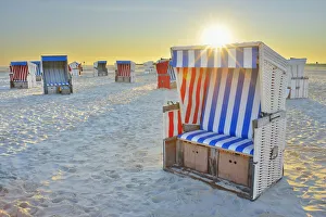 Sun Rising over Beach Chairs at Beach, Norderdeich, Sankt Peter-Ording, North Sea, Schleswig-Holstein, Germany Sun Rising over Beach Chairs at Beach, Norderdeich, Sankt Peter-Ording, North Sea, Schleswig-Holstein, Germany