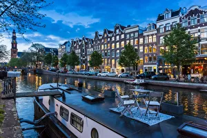 Table and chairs on top of a houseboat moored along the Prinsengracht canal at dusk in Amsterdam, Holland Table and chairs on top of a houseboat moored along the Prinsengracht canal at dusk in Amsterdam, Holland