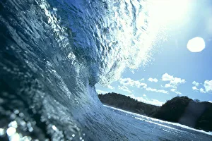 Translucent Curling Blue Wave Backlit, Shimmery Waters, Land In Background Translucent Curling Blue Wave Backlit, Shimmery Waters, Land In Background