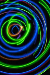 UK, Silhouette of woman spinning hula-hoop lit with LEDs in field at night; West Sussex UK, Silhouette of woman spinning hula-hoop lit with LEDs in field at night; West Sussex
