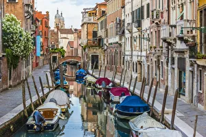 View of boats moored along a canal lined with historical buildings in Venice, Italy View of boats moored along a canal lined with historical buildings in Venice, Italy