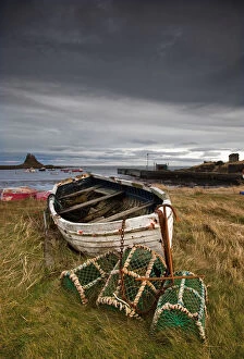 Images Dated 31st December 2011: A Weathered Boat And Fishing Equipment Sitting On The Shore With Lindisfarne Castle In The