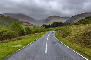 Winding country road and hills with overcast sky at Glen Nevis near Fort William in Scotland, United Kingdom Winding country road and hills with overcast sky at Glen Nevis near Fort William in Scotland, United Kingdom