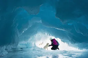 Woman With Her Pet Dog Inside A Natural Ice Cave On Frozen Lake Superior In Winter; Ontario, Canada Woman With Her Pet Dog Inside A Natural Ice Cave On Frozen Lake Superior In Winter; Ontario, Canada