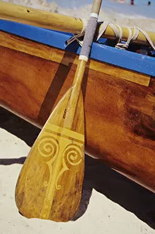 Wooden paddle and outrigger canoe on beach