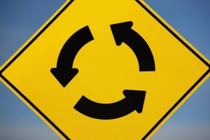 A Yellow Sign Showing Three Arrows Going In A Circle; Calgary, Alberta, Canada A Yellow Sign Showing Three Arrows Going In A Circle; Calgary, Alberta, Canada