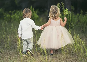 A Young Boy And Young Girl Holding Hands And Walking Through A Field; Tarifa, Cadiz, Andalusia, Spain A Young Boy And Young Girl Holding Hands And Walking Through A Field; Tarifa, Cadiz, Andalusia, Spain