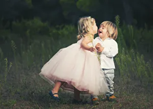A Young Girl With A Pink Princess Dress Leans In To Kiss A Young Boy; Tarifa, Cadiz, Andalusia, Spain A Young Girl With A Pink Princess Dress Leans In To Kiss A Young Boy; Tarifa, Cadiz, Andalusia, Spain