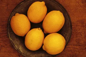 Lemon. Studio shot from above of five lemons on tin or pewter plate on wooden board Lemon. Studio shot from above of five lemons on tin or pewter plate on wooden board