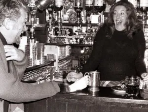 A barmaid at the Red Lion Pub in Kings Langley, Hertfordshire laughing after customer A barmaid at the Red Lion Pub in Kings Langley, Hertfordshire laughing after customer