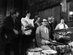 The Bee Gees pop group stand behind a vicar having a a go on the drums during rehearsals The Bee Gees pop group stand behind a vicar having a a go on the drums during rehearsals