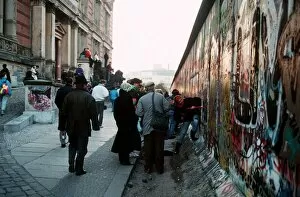 Berlin Wall in Germany with people chipping bits off the wall for souvenirs