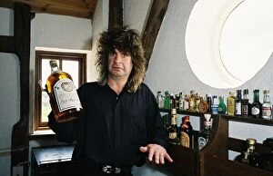 Images Dated 27th May 1988: Black Sabbath singer Ozzy Osbourne holding a large bottle of whiskey at his home