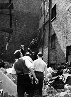 When a building was hit in a raid on this country firemen lowered an injured man from When a building was hit in a raid on this country firemen lowered an injured man from