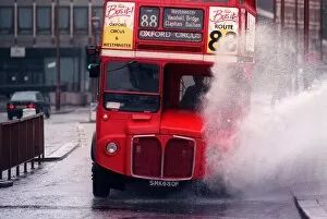 A bus splashing through a large puddle of water after a heavy rainfall in London
