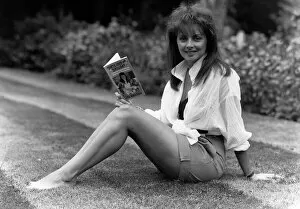 00126 Gallery: Carol Vorderman TV Presenter sitting on grass lawn holding paperback book