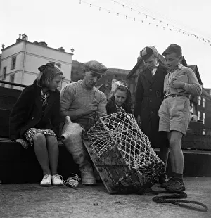 Children watching a fisherman at work with his net. North Yorkshire coast Children watching a fisherman at work with his net. North Yorkshire coast